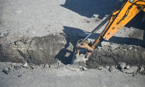 Excavator digging a trench in the road